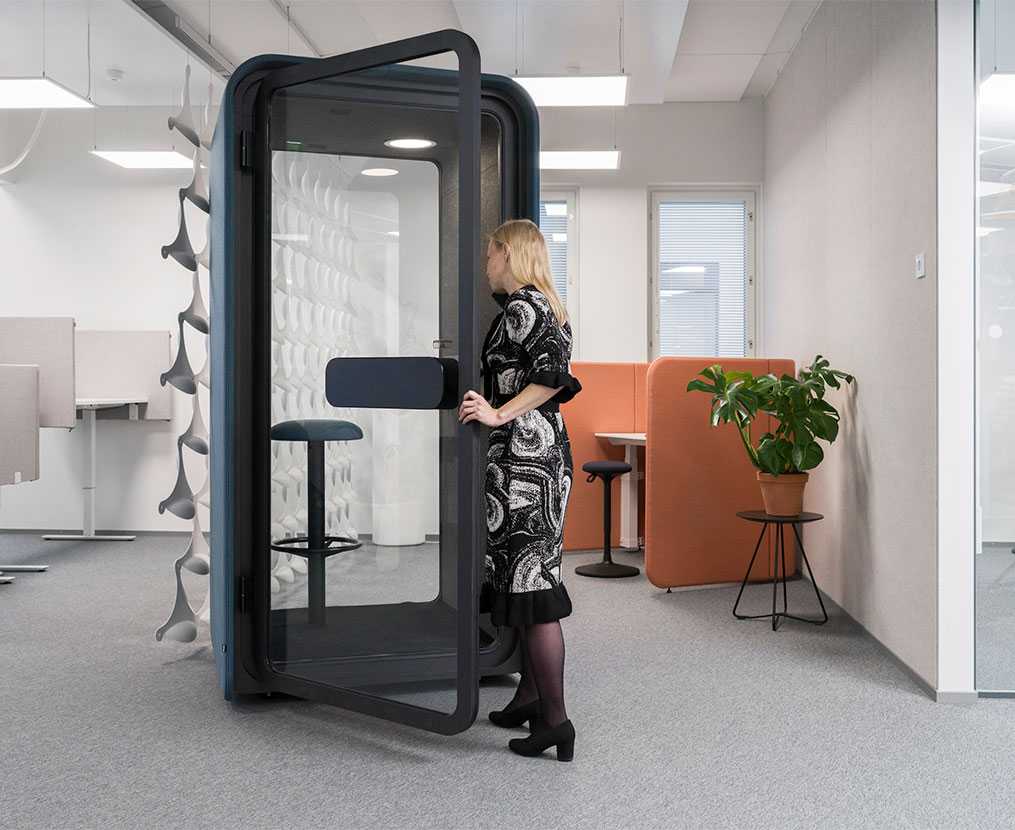 En kvinna går in i en PodBooth-telefonkiosk för att prata i telefon