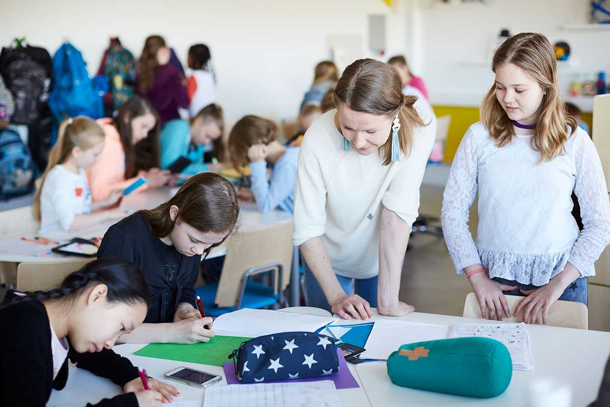 Teacher and pupils studying on Martela's Salmiakki tables and Grip chairs at English School in Helsinki