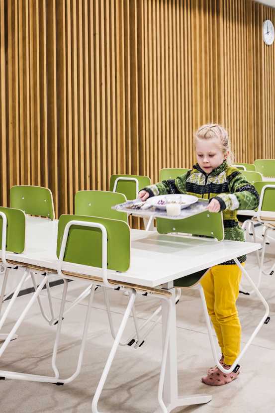 A pupil lifting a tray to the table