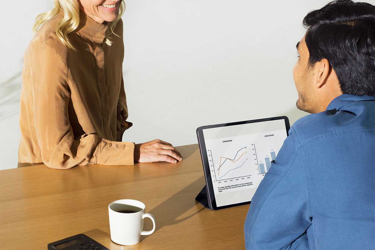 Two people sitting around a table looking at an ipad