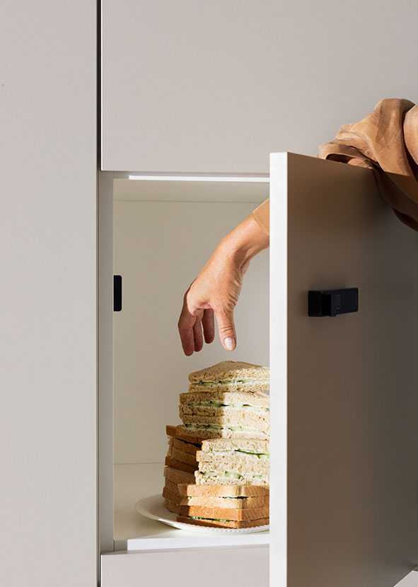 A hand reaches for a sandwich from the Capa cabinet