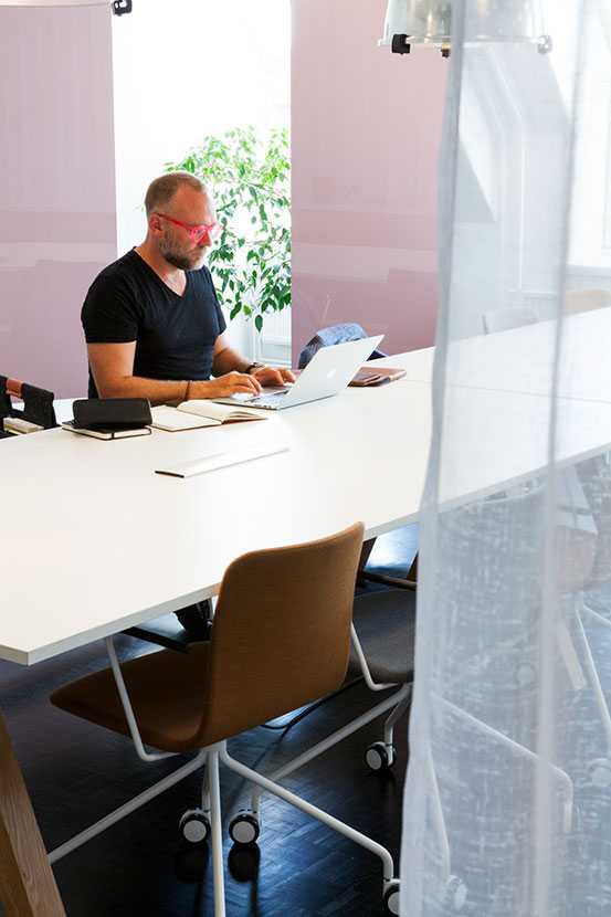Man working on Martela's Frankie table and Sola chair at SFB & DQC's office in Helsinki