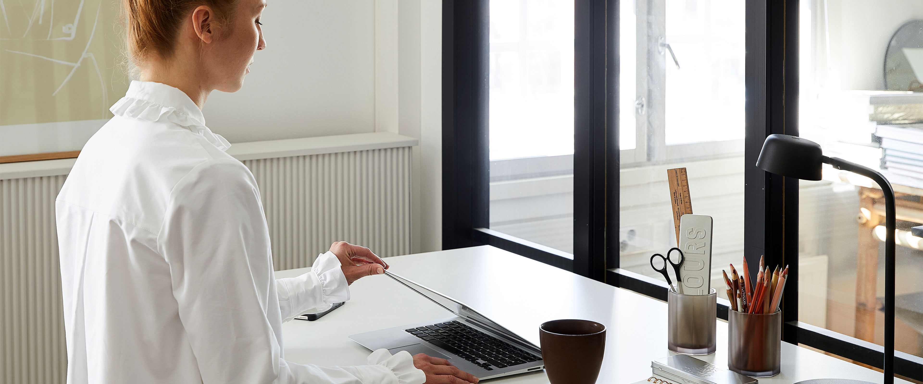 Woman opening laptop in home office